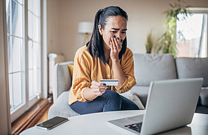 Lady covering her mouth and holding a bank card